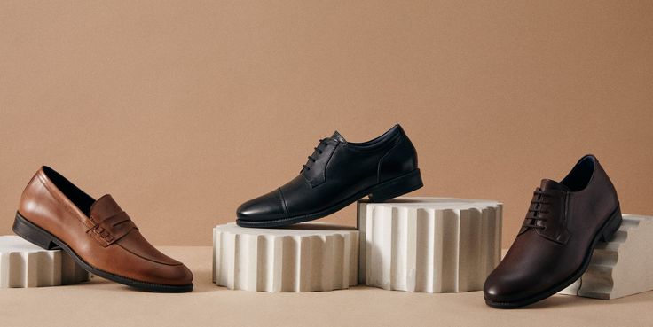 Three pairs of men's dress shoes on a beige background